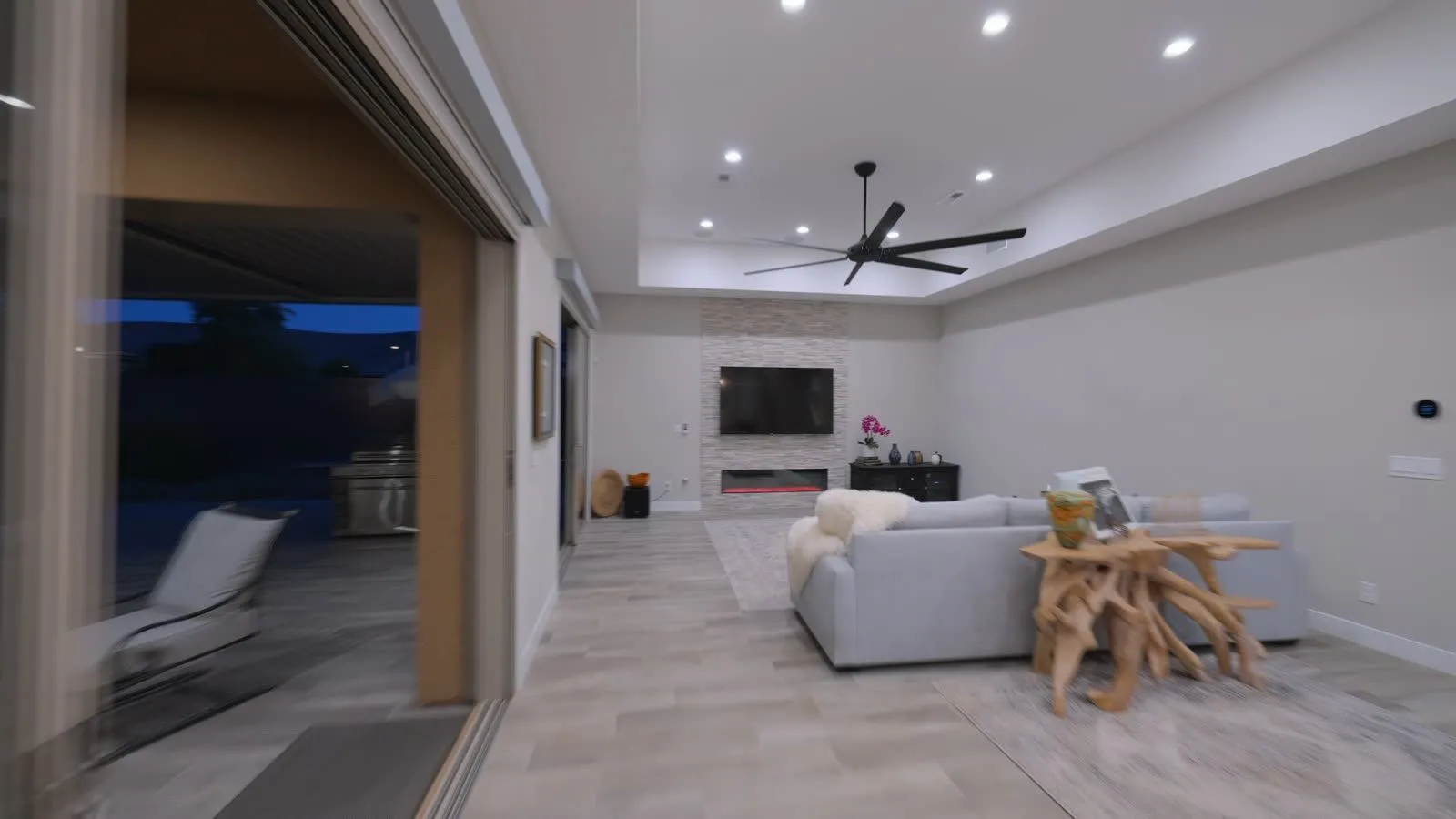 Open living room with stacked-stone fireplace wall and sliding glass doors to the patio