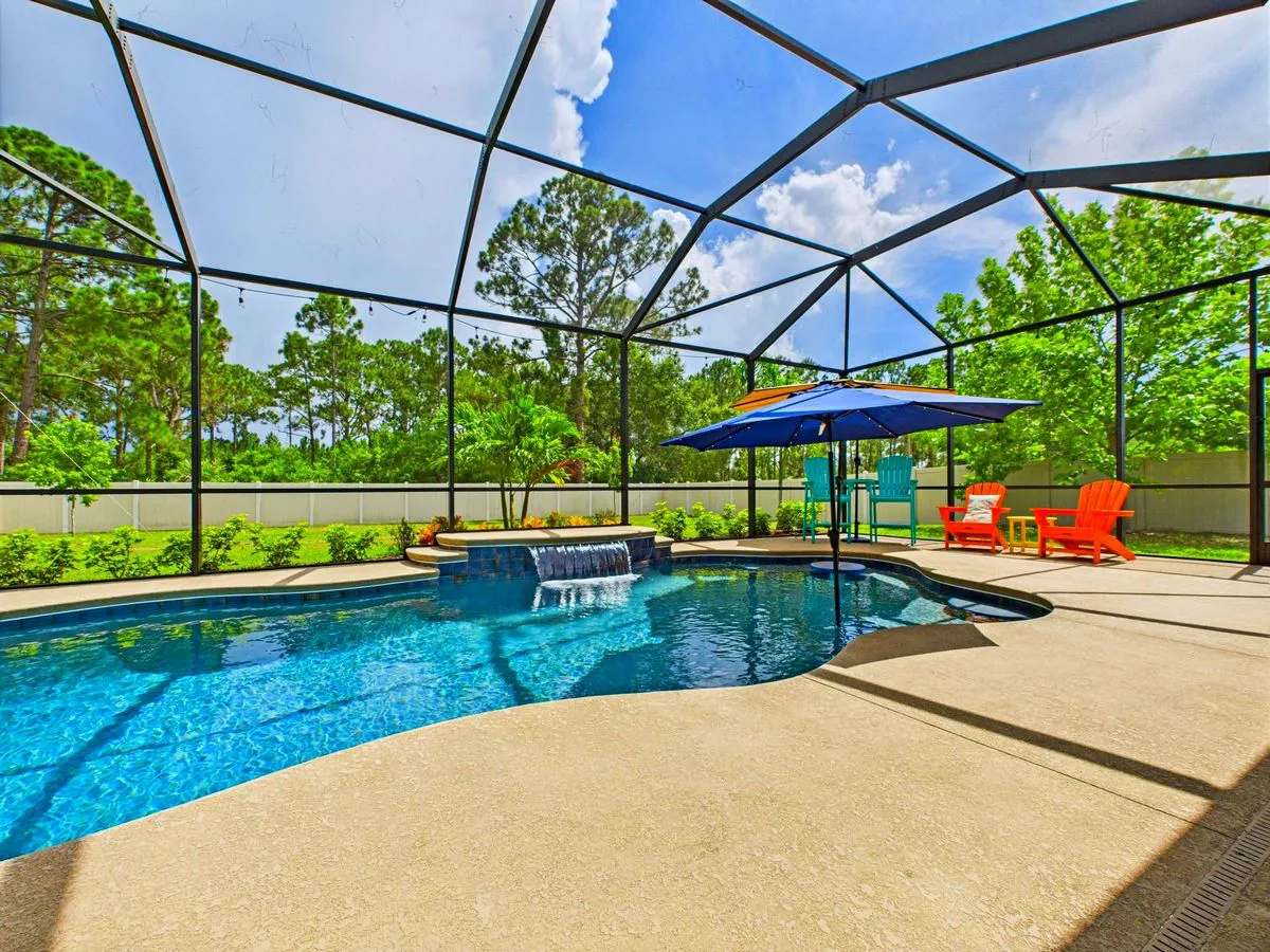 Backyard swimming pool surrounded by a screened patio