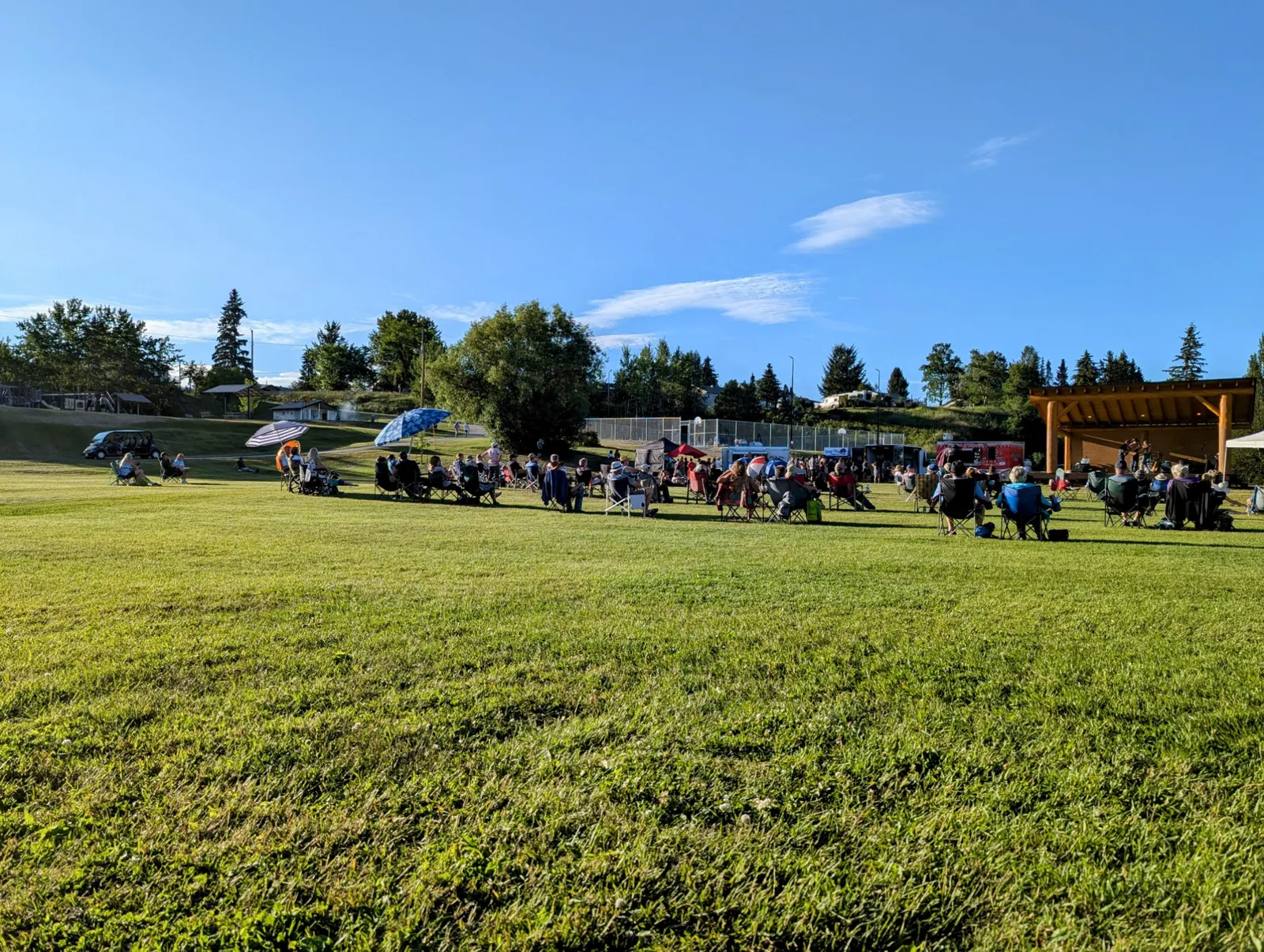 Audience seated on the lawn for an outdoor performance in 100 Mile House