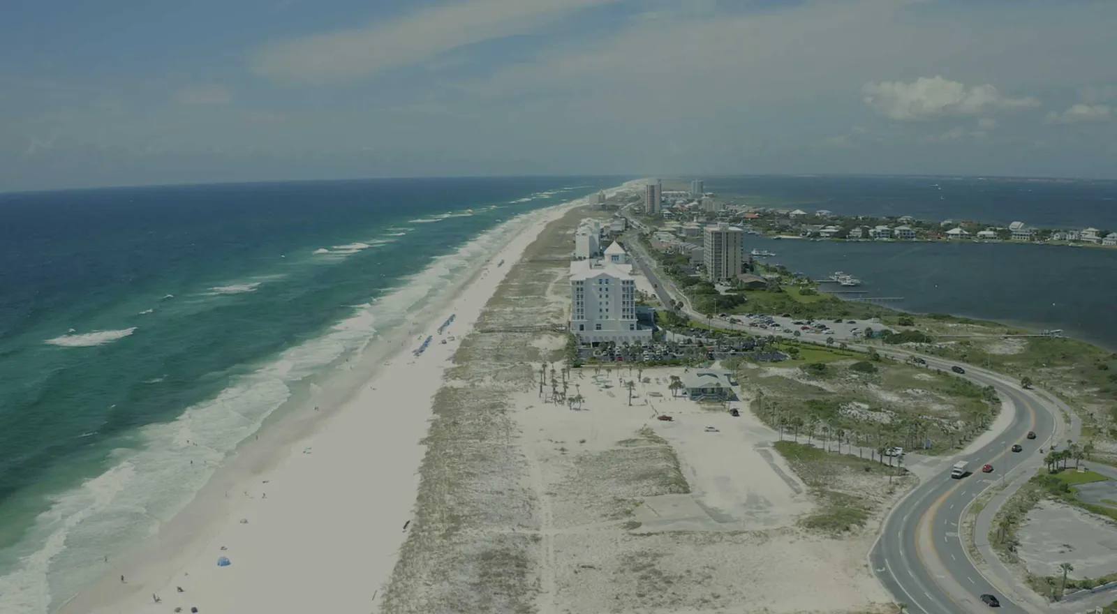 drone view of blue-green water, white sands and Pensacola Beach condos