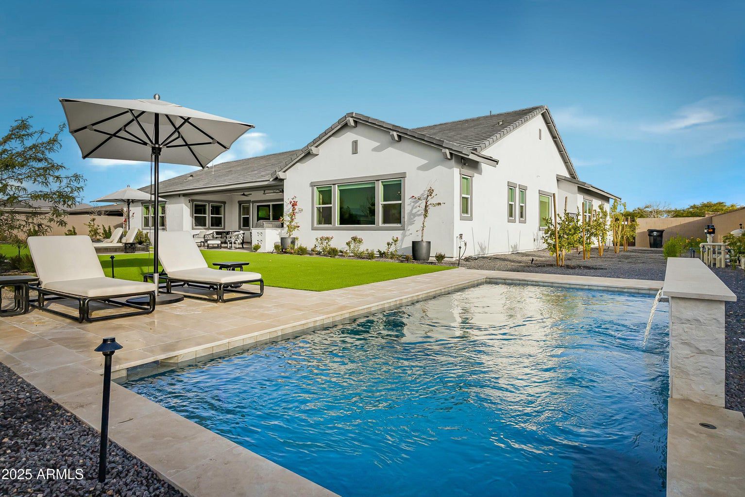 Private backyard swimming pool with lounge chairs and a covered patio