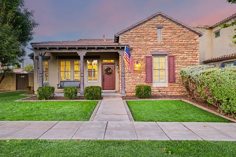 Twilight exterior with a stone facade, front porch and landscaped lawn