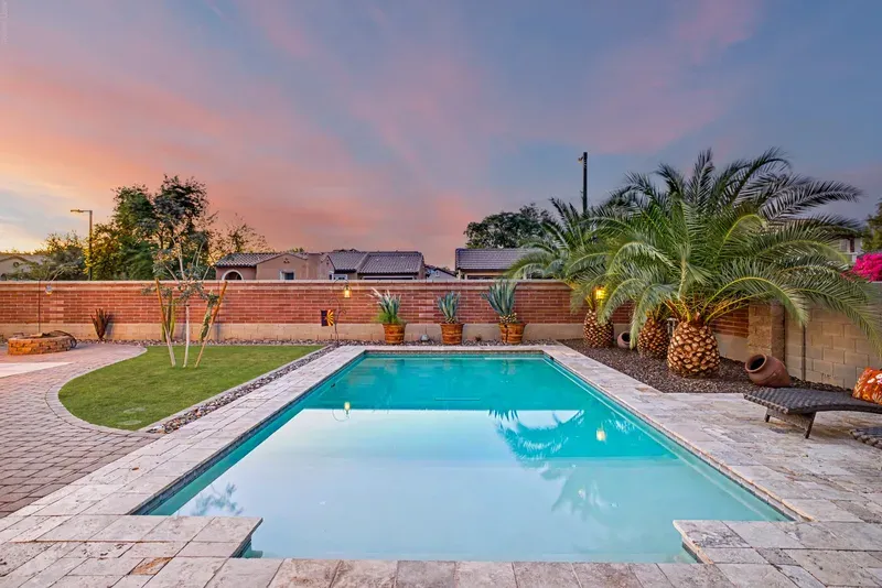 Backyard swimming pool and palm trees at sunset